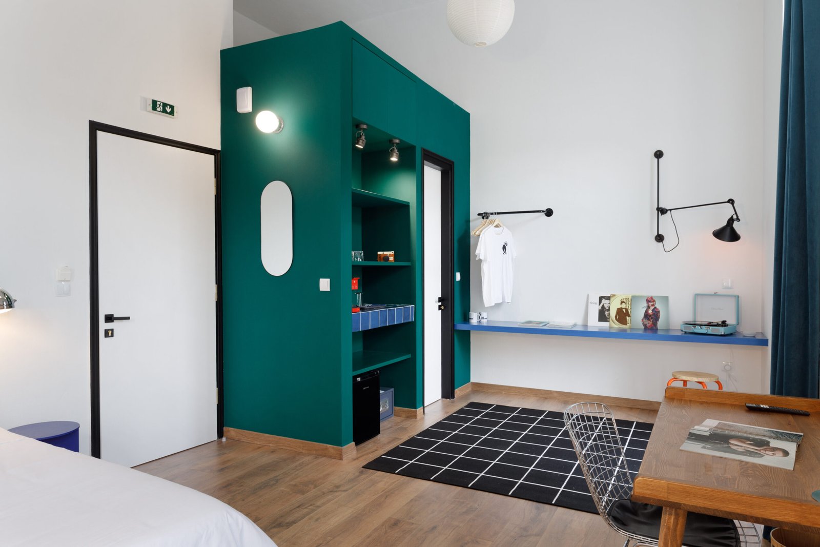lounge area of baroness 1, with a green closet, a wooden working desk with a metal chair and a blue desk with vinyl player on