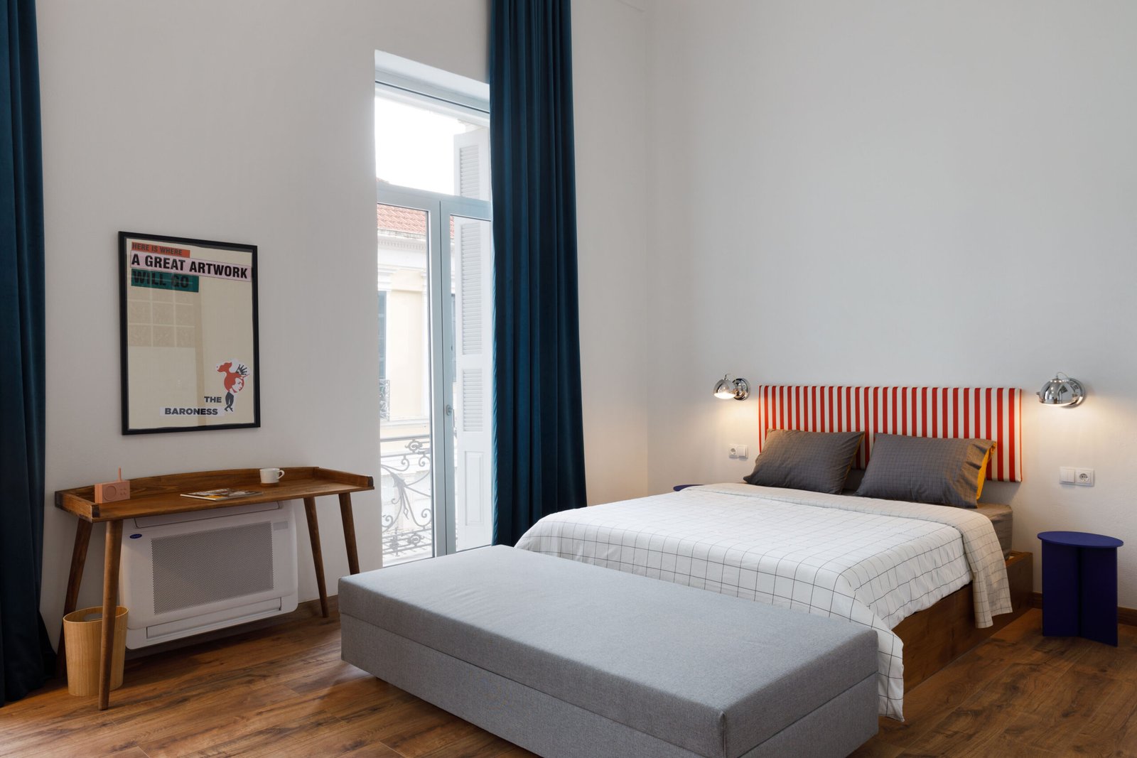 interior of baroness 2 showing the wooden desk, the double bed with grey and white linen, the blue curtain and the wooden floor
