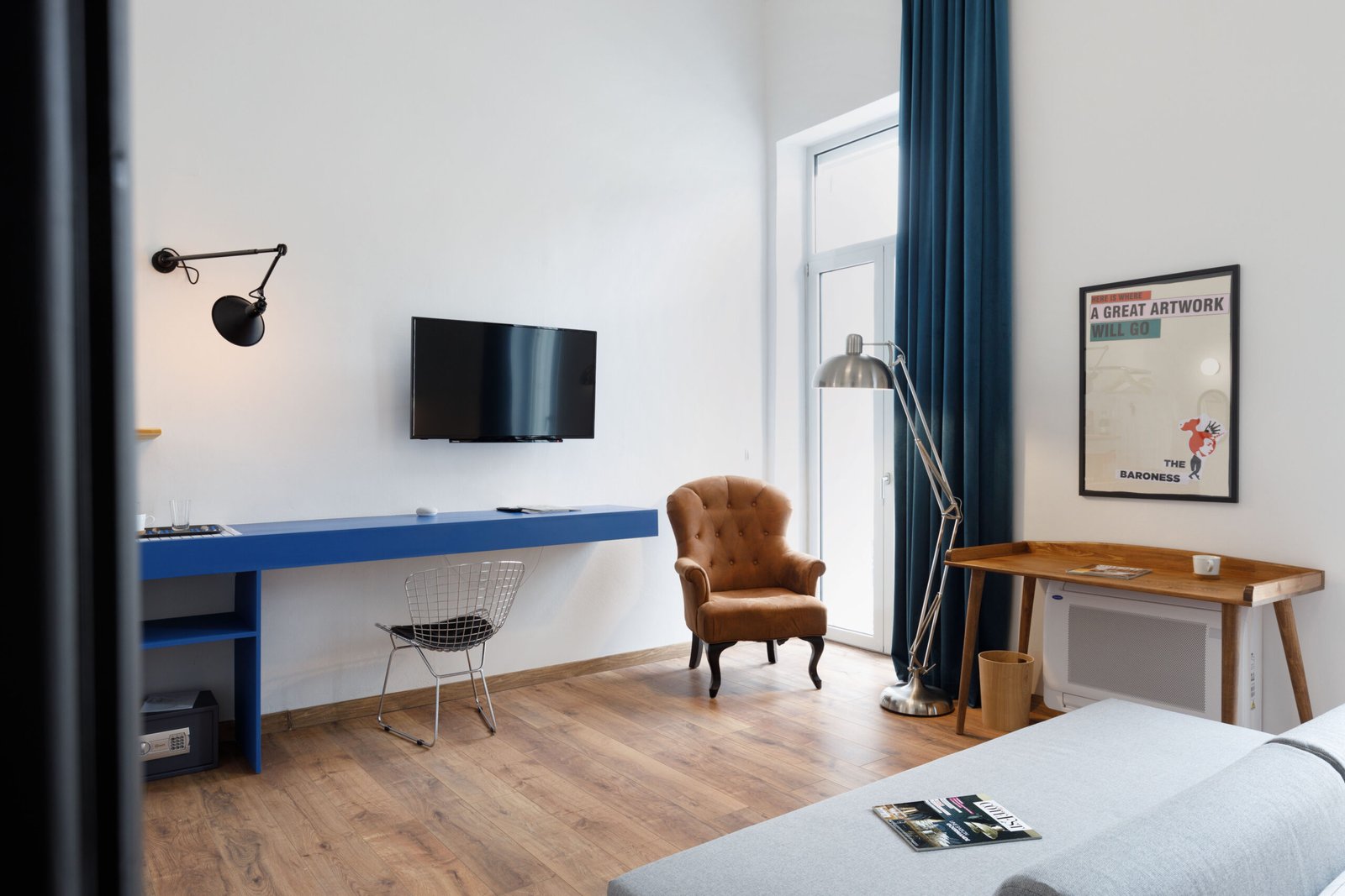 lounge area of baroness 2, showing tv, a blue desk, a wooden working desk and a vintage armchair