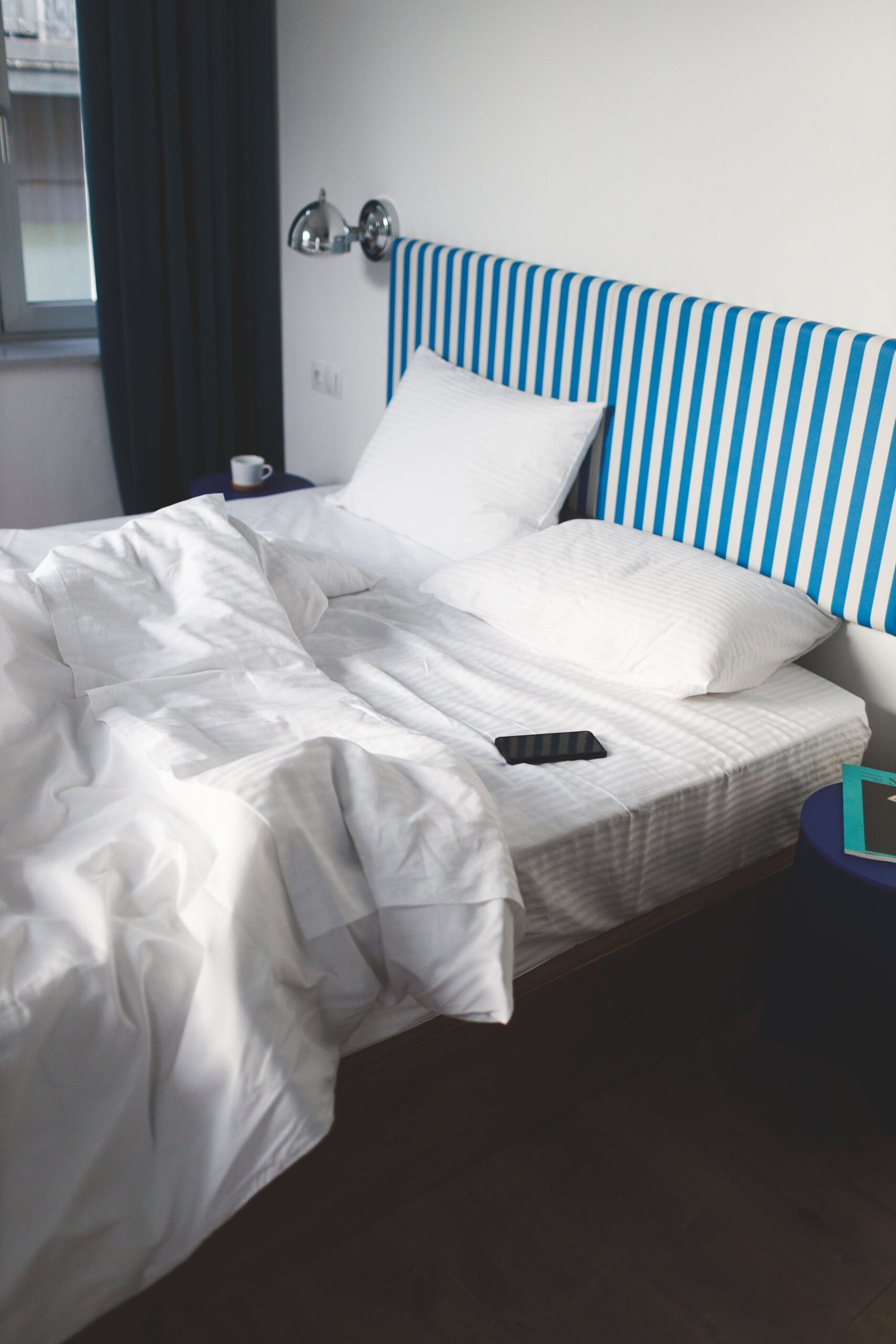 artistic view of the bed of baroness 1 with messy sheets on the bed and a white and blue headboard